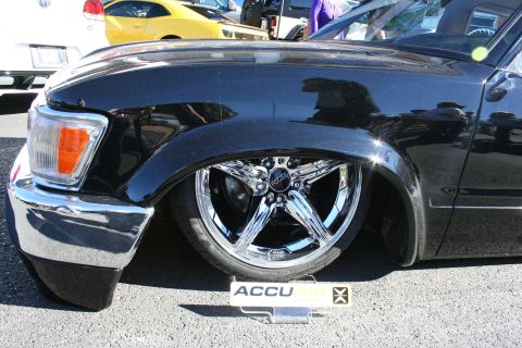 1998 Ford Crown Victoria - Close-up of a black lowered vehicle's front fender sitting over a polished five-spoke chrome wheel and tire.