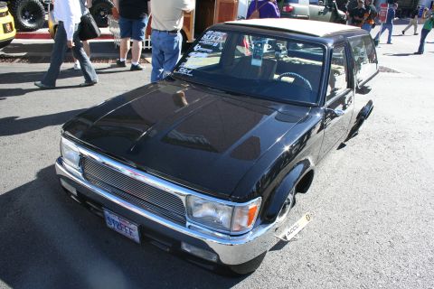 1998 Ford Crown Victoria - black lowered compact pickup with a chrome billet grille and white roof parked on pavement at an outdoor show.