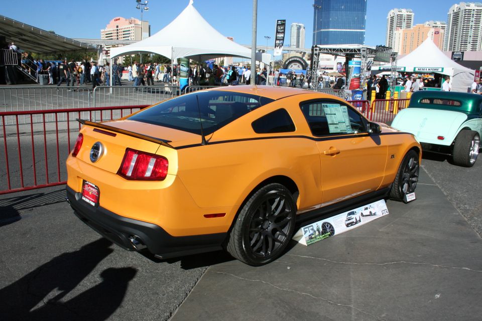 Orange Ford Mustang coupe rear quarter view at an outdoor event