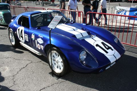 1998 Ford Crown Victoria - blue Cobra Daytona-style coupe with white stripes and racing number 14 displayed outdoors behind a barrier.