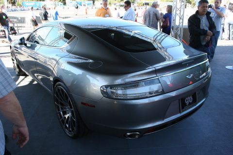 1998 Ford Crown Victoria - Rear three-quarter view of a gray Aston Martin Rapide four-door on a platform amid a crowd of onlookers.
