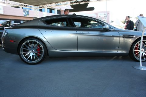 1998 Ford Crown Victoria - Side profile of a gray Aston Martin Rapide four-door on chrome multi-spoke wheels with red brake calipers.