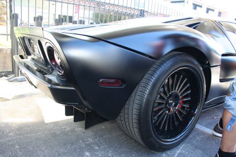 1998 Ford Crown Victoria - Rear three-quarter view of a matte-black Ford GT showing round taillights and black wheels with red calipers.