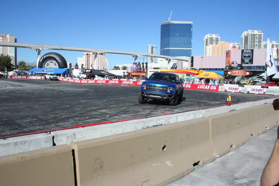 Blue Ford Raptor pickup on an outdoor demo course with Las Vegas high-rises behind