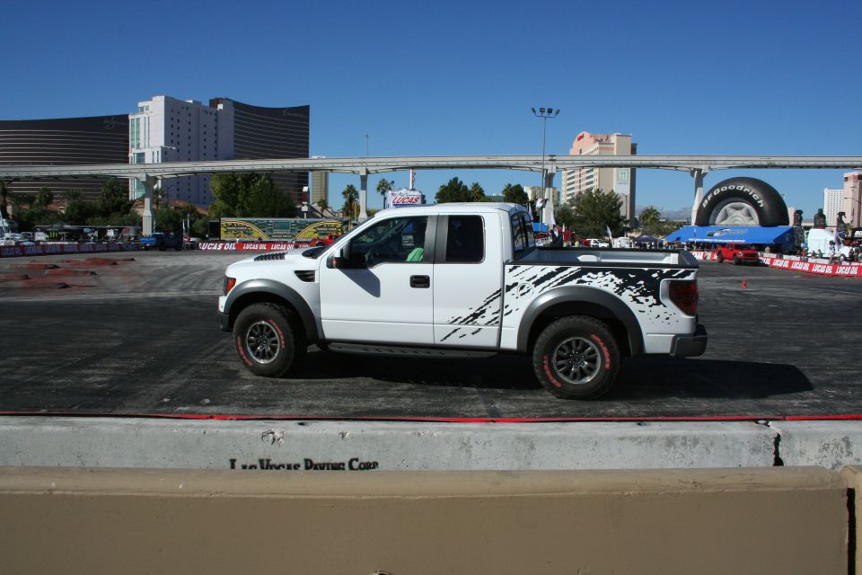 White Ford Raptor pickup side profile with splatter graphics on a course