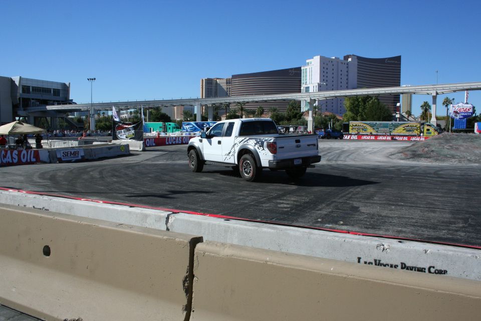 White pickup driving away on a dirt course ringed by Lucas Oil banners in Las Vegas