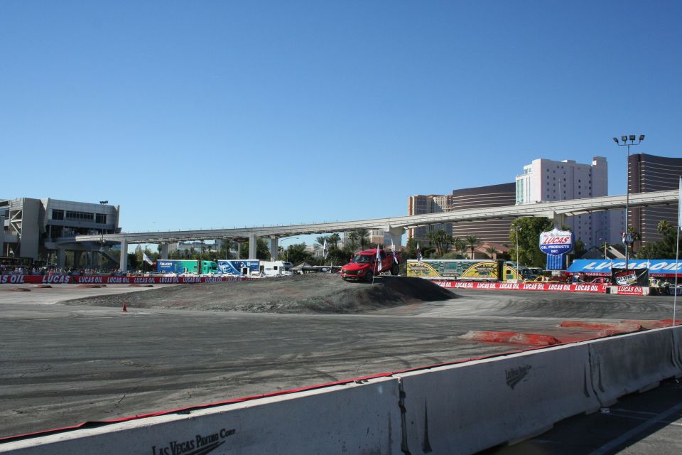 Graded dirt course with a red van and Lucas Oil banners, Las Vegas skyline behind