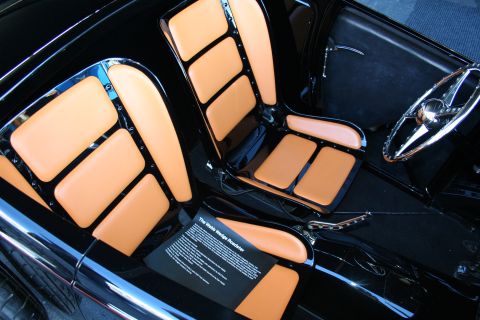 1998 Ford Crown Victoria - Close interior view of a hot rod showing tan-and-black upholstered seats, a chrome steering wheel, and a small descriptive placard.
