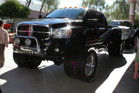1998 Ford Crown Victoria - lifted black Dodge Ram diesel pickup with a chrome brush guard, roof lights, and large off-road tires on display.