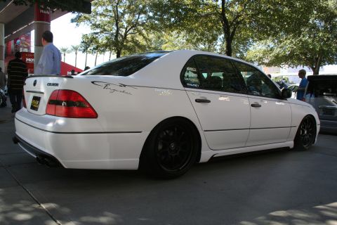 1998 Ford Crown Victoria - Rear three-quarter view of a white lowered sedan on black wheels with twin exhaust tips parked beside a building.