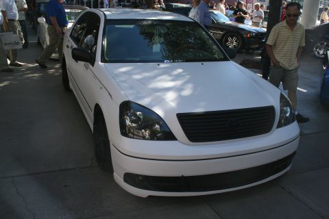 1998 Ford Crown Victoria - Front three-quarter view of a white Lexus LS sedan with a blacked-out grille and smoked headlights at a crowded outdoor show.