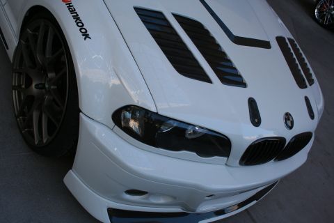 1998 Ford Crown Victoria - Tight front-corner view of a white BMW M3 showing the kidney grilles, louvered vented hood, splitter and a Hankook tire.