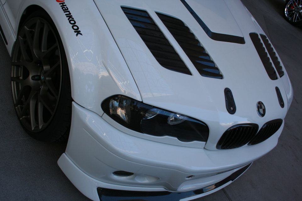 Close front view of white BMW M3 with louvered hood and Hankook tire
