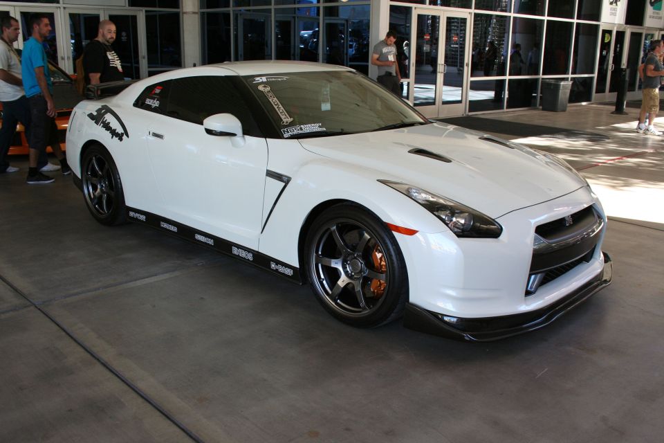 White Nissan GT-R coupe with black wheels and sponsor decals outside venue