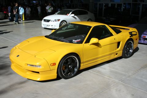 1998 Ford Crown Victoria - yellow Acura NSX mid-engine sports car with black wheels and aero body kit parked on pavement, a white coupe behind it at a car show.