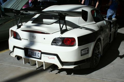 1998 Ford Crown Victoria - Rear view of a white Honda S2000 track car with a tall GT wing, diffuser and a SZKRA C license plate, surrounded by people.