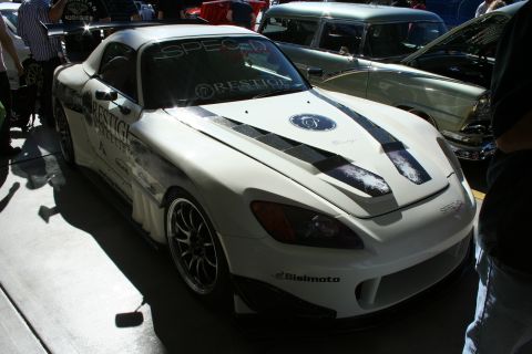 1998 Ford Crown Victoria - Front three-quarter view of a white Honda S2000 widebody race car with a black carbon hood and Prestige/Bisimoto graphics indoors.