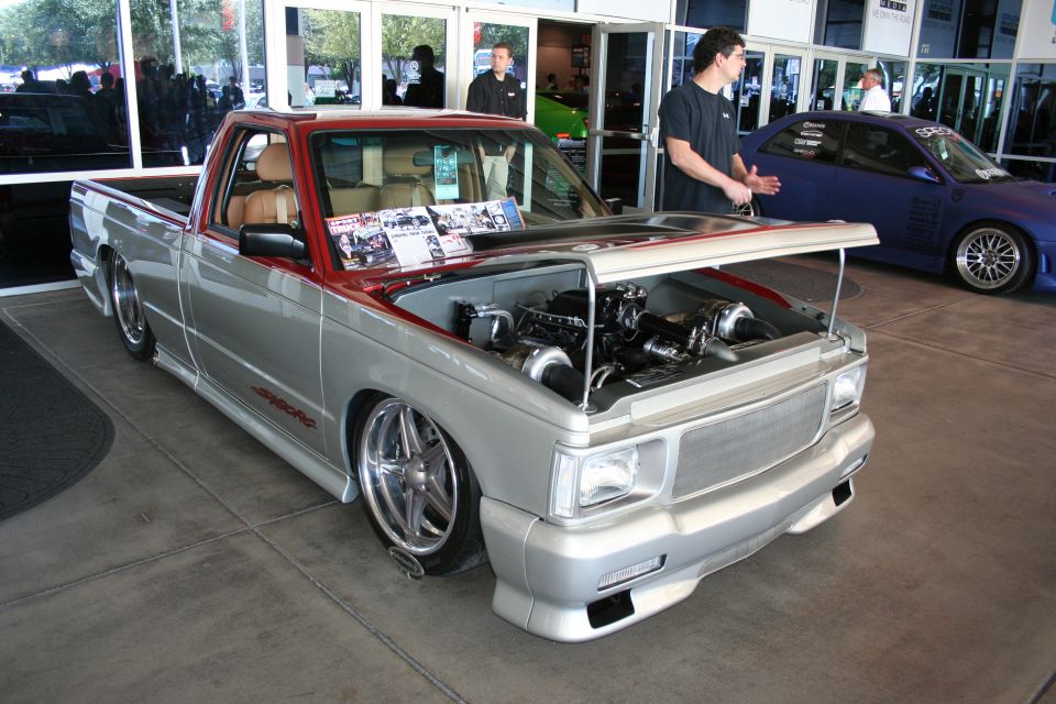 Lowered silver GMC pickup with open hood showing twin-turbo engine