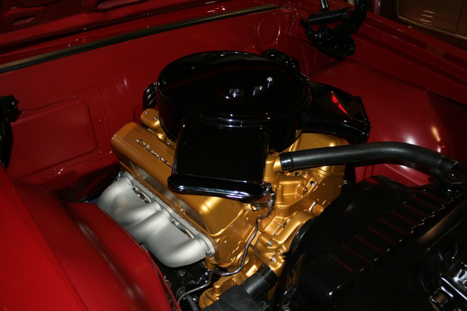 Gold-painted V8 engine with black air cleaner in red car engine bay