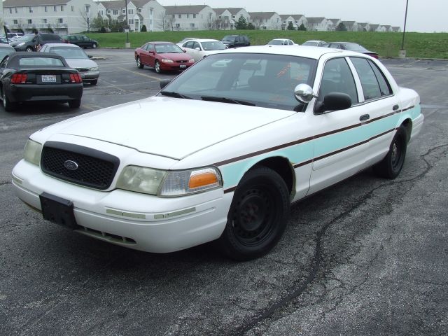 White Ford Crown Victoria sedan with teal side stripe and black steel wheels, front 3/4 view in a parking lot