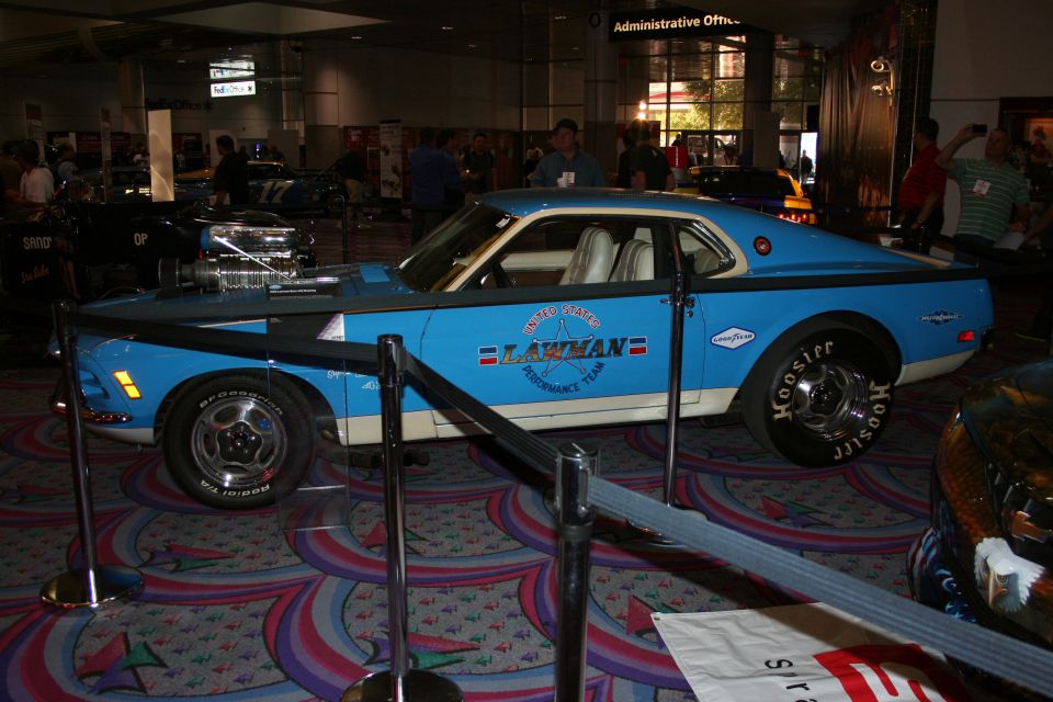 Blue and white vintage muscle car with supercharger and Lawman graphics at indoor show