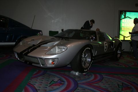 1998 Ford Crown Victoria - silver mid-engine GT40-style race car with twin blue stripes and a roundel reading '5' displayed in a dim exhibit hall.