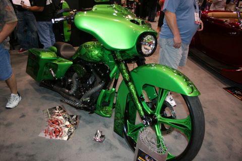 1998 Ford Crown Victoria - lime-green custom bagger motorcycle with a large front wheel, fairing, etched bodywork and saddlebags displayed on grey carpet indoors.