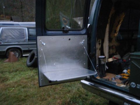 1981 Ford E350 - A fold-down shelf is installed inside a van, with another vehicle visible in the background.