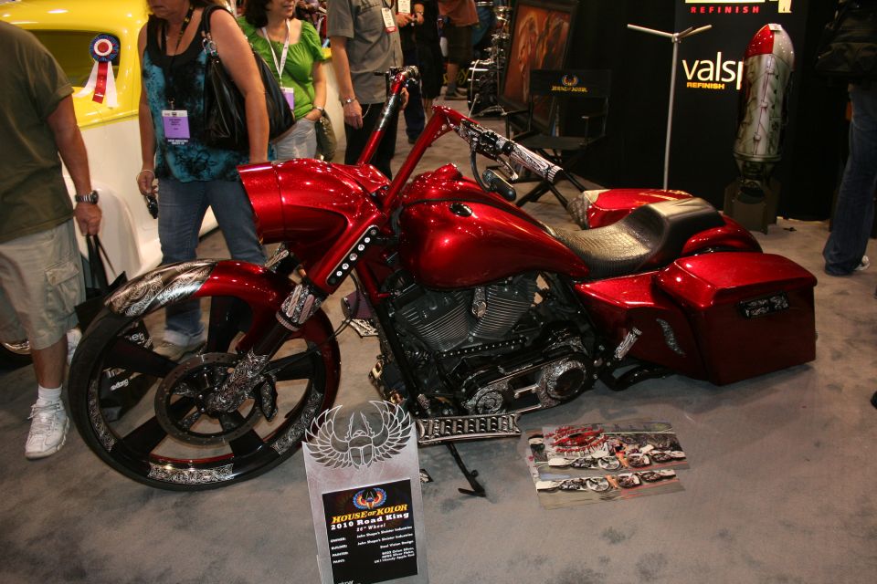 Candy-red custom bagger motorcycle with big front wheel and trophy at show