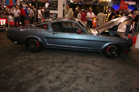 1998 Ford Crown Victoria - Side view of a slate-gray fastback muscle car with black wheels and red brake calipers parked on show carpet.