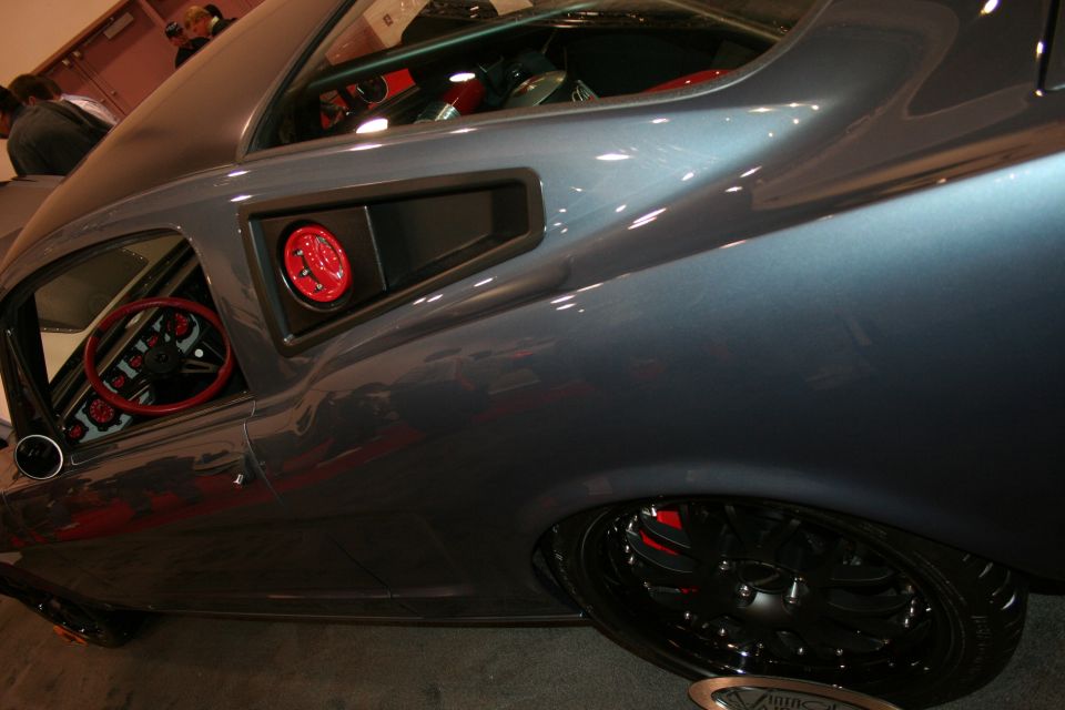 Close-up of gray muscle car rear quarter window and red interior detail