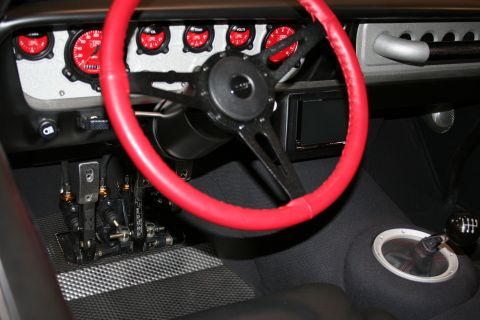 1998 Ford Crown Victoria - Interior of a custom car showing a red-wrapped steering wheel, row of black-faced gauges, and floor-mounted pedals.