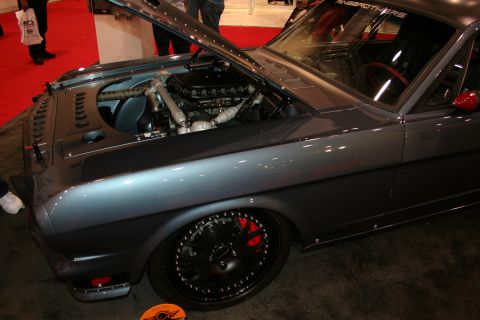 1998 Ford Crown Victoria - Side-front view of a gray custom fastback with open hood showing engine, black wheel, and red brake caliper.
