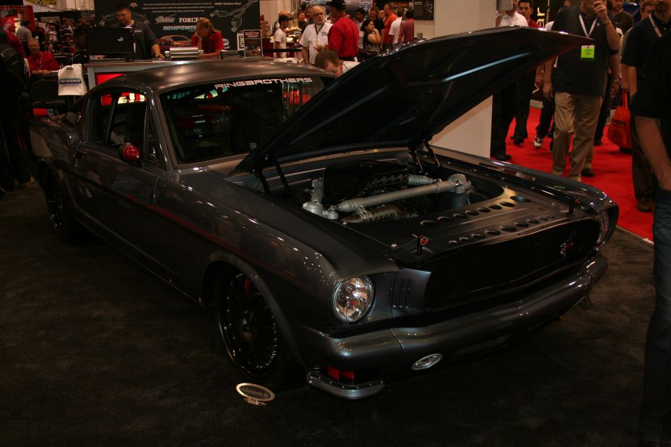 Front of a dark gray custom fastback with open hood at a show