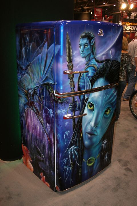 1998 Ford Crown Victoria - compact refrigerator custom-painted with blue alien-warrior fantasy artwork displayed at a trade show booth.