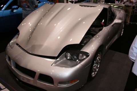 1998 Ford Crown Victoria - silver custom sports car with a tall raised hood scoop and quad pop-up-style headlights displayed at a show.