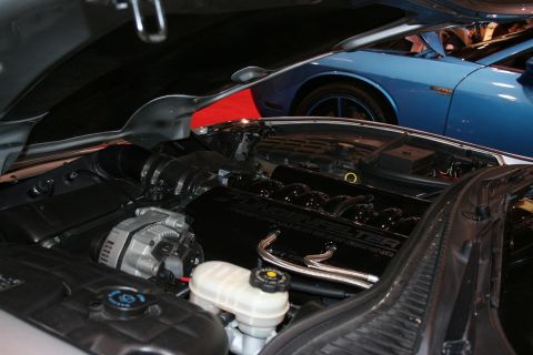 1998 Ford Crown Victoria - Engine bay of a custom car showing chrome plumbing, a black engine cover, and a white fluid reservoir.