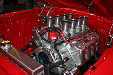 1998 Ford Crown Victoria - custom V8 engine fitted with eight individual velocity-stack throttle bodies and red plug wires in a red engine bay.