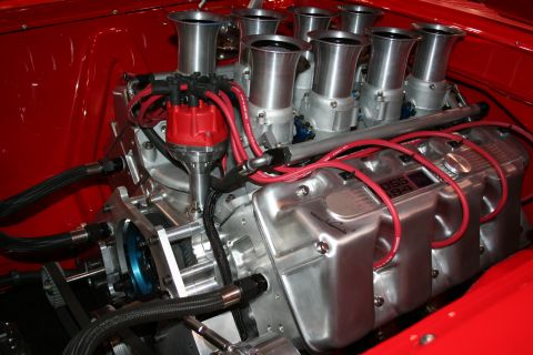 1998 Ford Crown Victoria - polished V8 engine fitted with eight individual chrome velocity-stack intake trumpets and red plug wires sits in a glossy red engine bay.