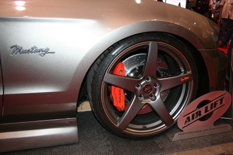 1998 Ford Crown Victoria - Close-up of a silver Mustang's front wheel showing a bronze five-spoke rim, red Baer brake caliper, and a Mustang script fender badge.