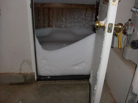 1995 Ford Bronco - A large snowdrift has completely blocked a doorway, with indoor utilities visible on the right side.