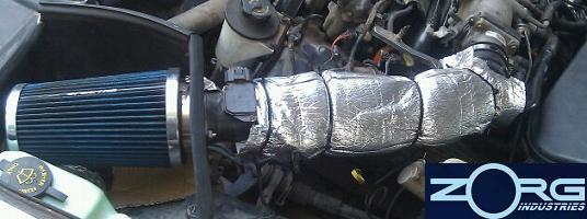 Aftermarket blue air filter and silver-wrapped intake tubing in engine bay