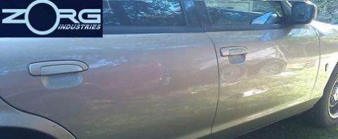 2000 Mercury Grand Marquis - The side of a car is shown, door handles and a reflection of trees and sky.