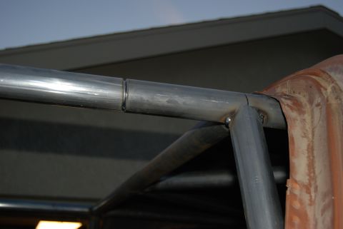 1982 Ford Bronco - Close-up view of welded roll cage tubing and a section of rusty metal paneling.