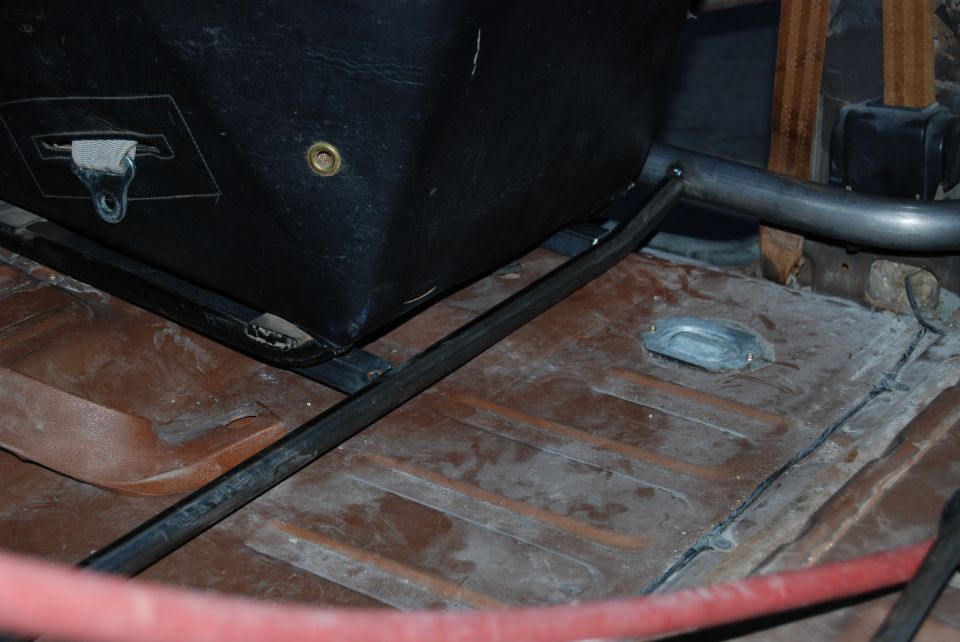 Interior view of a black seat base and metal roll cage tubing