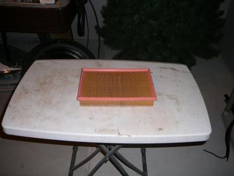 1997 Mercury Grand Marquis - An air filter sits on a table, with a Christmas tree and a vehicle part visible in the background.