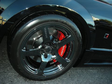1998 Ford Crown Victoria - Close-up of a black machined five-spoke wheel and red Roush-branded brake caliper on a black vehicle.