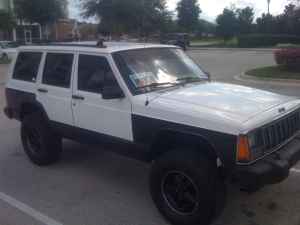 1992 Jeep Cherokee - A white and black 1992 Jeep Cherokee is parked outdoors, showing its front and side profile.