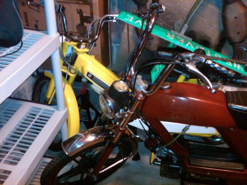 1981 Garelli Rally Sport - Two mopeds, a red one with Garelli branding and a yellow one, are parked next to each other.