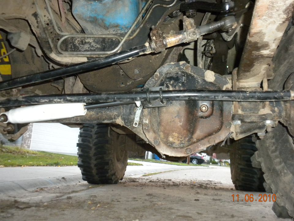 Undercarriage view showing steering linkage, differential, and a white shock absorber. Tires are visible